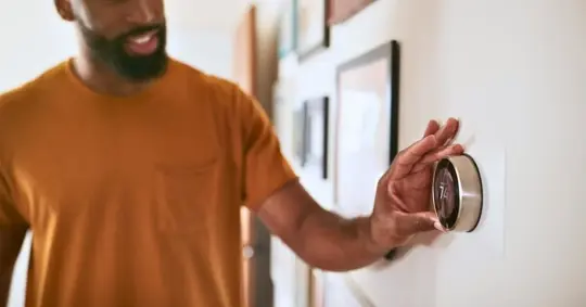 Man adjusting thermostat settings